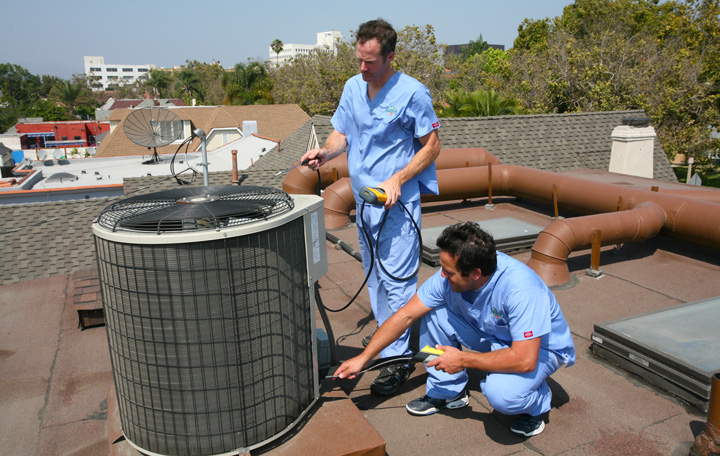 Two Energy Doctors performing maintenance on a rooftop HVAC unit